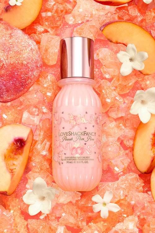 Pink bottle with silver cap on a decorative background with peach slices and flowers