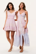 Two women wearing pastel mini and maxi dresses on a white background