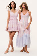 Two women wearing pink and white mini and maxi dresses on a plain background