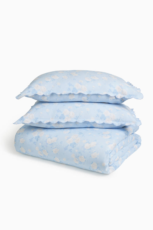 Stack of light blue bedding with floral pattern on a white background