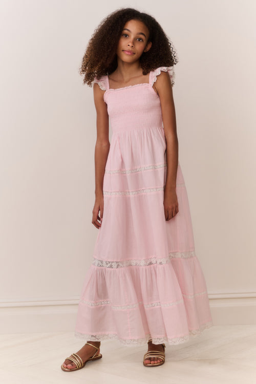 Young girl wearing a pink dress with ruffled sleeves against a white background