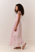 Young girl wearing a pink dress with ruffled sleeves against a white background