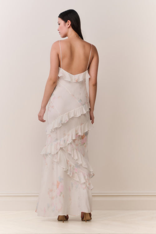 Woman wearing a white floral ruffle tiered sleeveless dress against a plain background