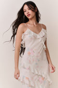 Woman wearing a white floral ruffle tiered sleeveless dress against a plain background