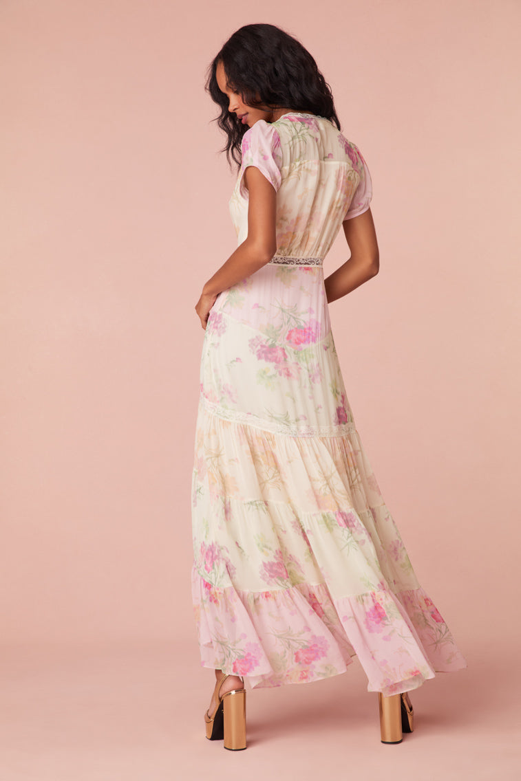 Maxi dress with a floral print mix in pink, cream, and light green. This dress begins with a v-neckline and a lace-trimmed waist seam, falling to a flowy skirt.