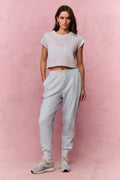Woman wearing a light blue floral t-shirt and sweatpants against a pink background