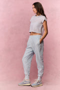 Woman wearing a light blue floral t-shirt and sweatpants against a pink background