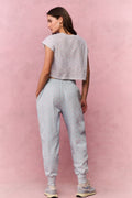 Woman wearing a light blue floral t-shirt and sweatpants against a pink background