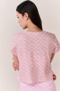 Woman wearing a pink bow patterned t-shirt and matching leggings outfit against a plain background