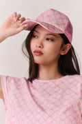 Woman wearing a pink bow print cap and matching tee against a white background