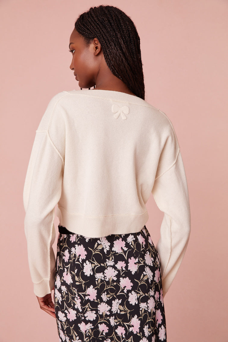 This lightweight, slightly cropped knit is designed from a cashmere fabric with rib linking near the seams and sealed with a self top-applied bow on the back. 