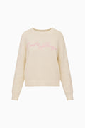 Beige sweater with pink LoveShackFancy text on a white background
