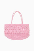 Pink woven handled bag against white background