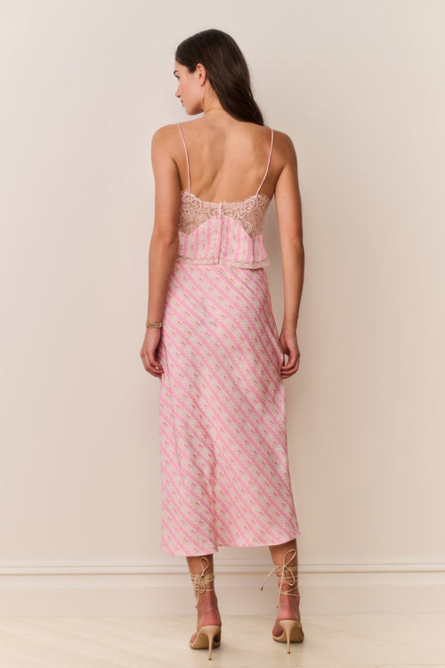 Woman wearing a pink patterned matching skirt and camisole with a white background