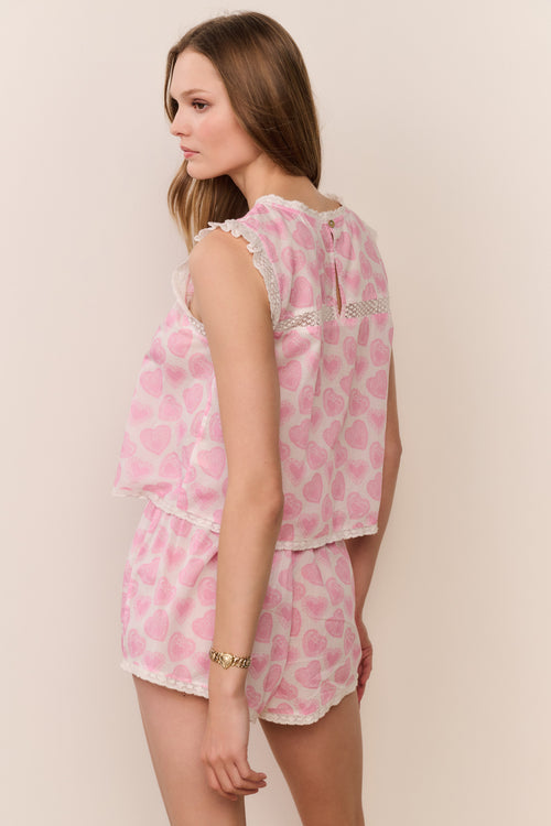 Woman wearing a pink printed pajama set against a beige background