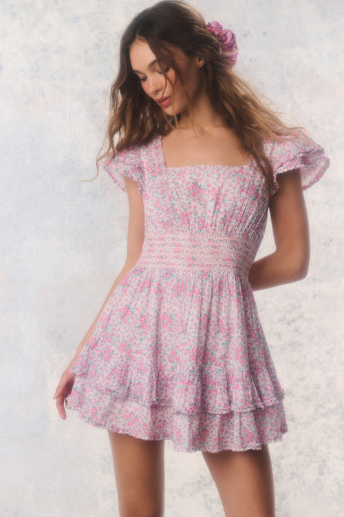 Woman wearing a pink floral dress against a light background