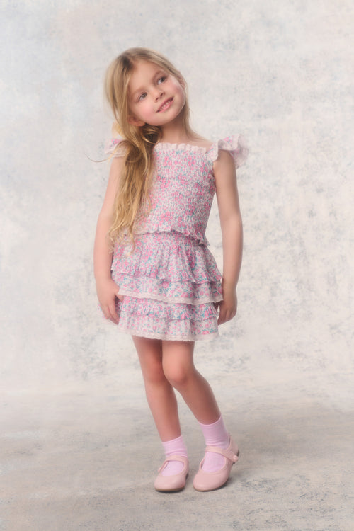 Young girl wearing a pink floral dress against a light background