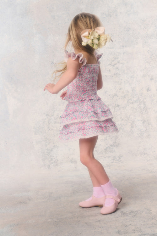 Young girl in a floral dress standing on a light background