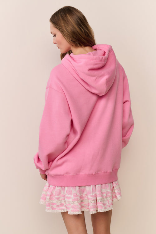 Person wearing a pink hoodie and skirt with a plain background