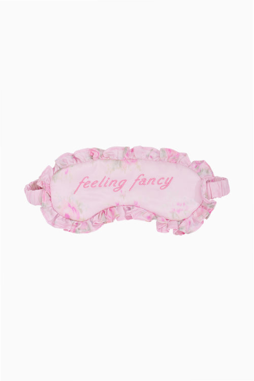 Pink sleep mask with floral pattern and 'feeling fancy' text on a white background