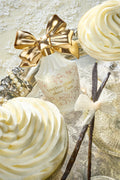 White perfume vanity bottle with gold bow topper and decorative swirls, LoveShackFancy.