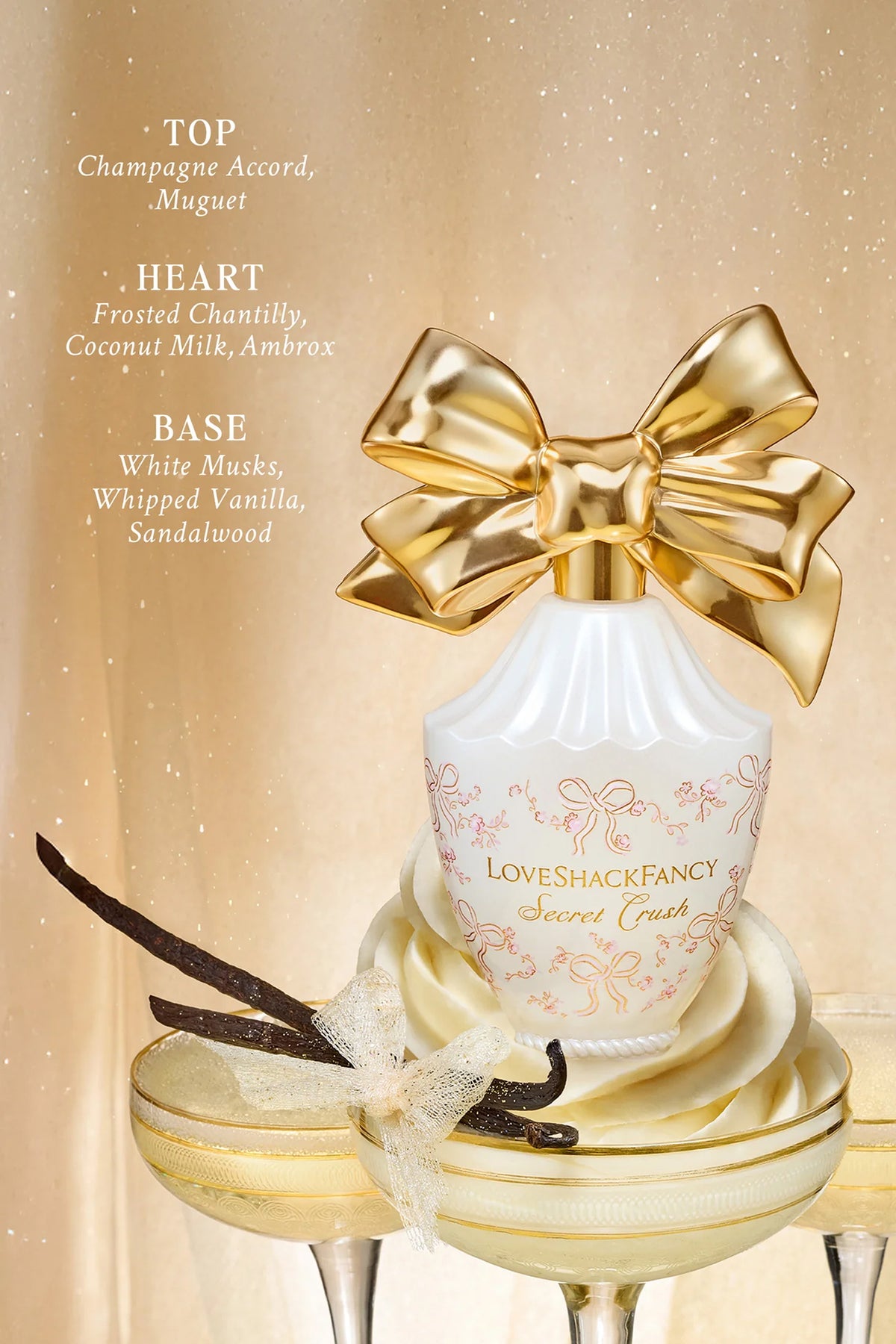 White LoveShackFancy perfume bottle with large gold bow, heart design and ribbon accents.