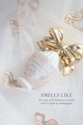 White LoveShackFancy perfume bottle with gold bow and pink ornamental script on pouch.