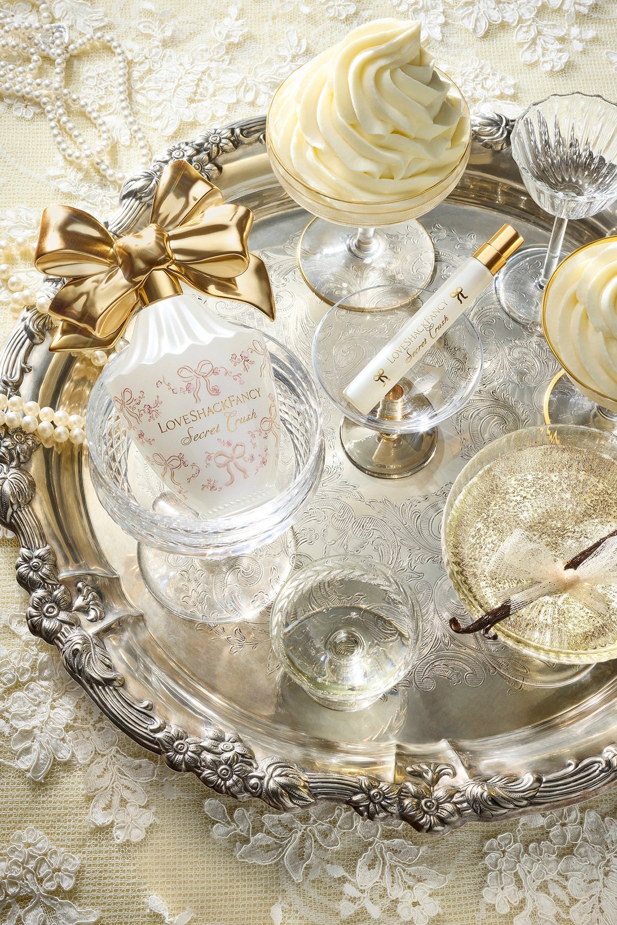 Vanity set tray with white perfume bottle, gold bow accents, and matching sprayer, LoveShackFancy.