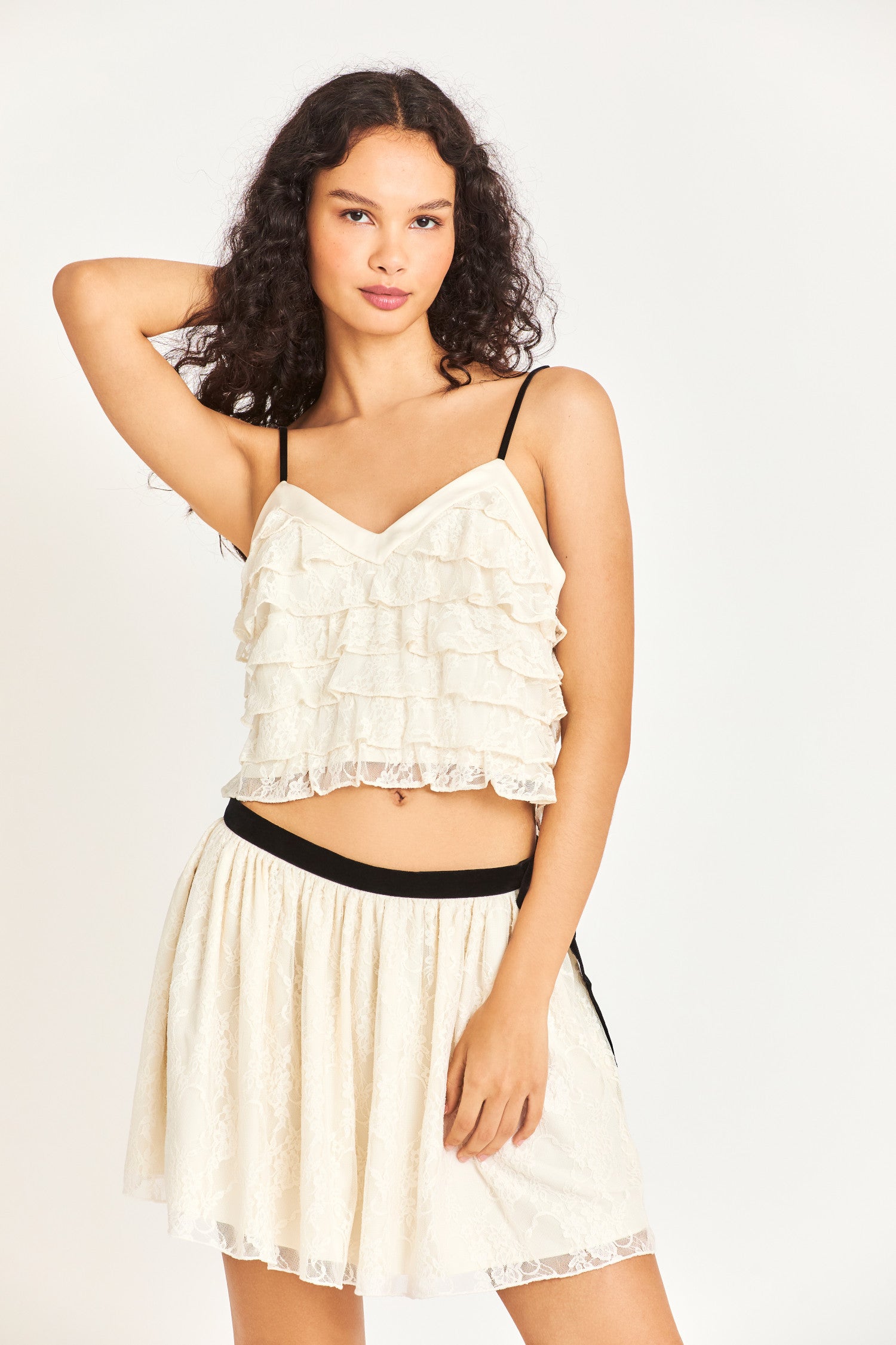 Model wearing white ruffle top with black straps