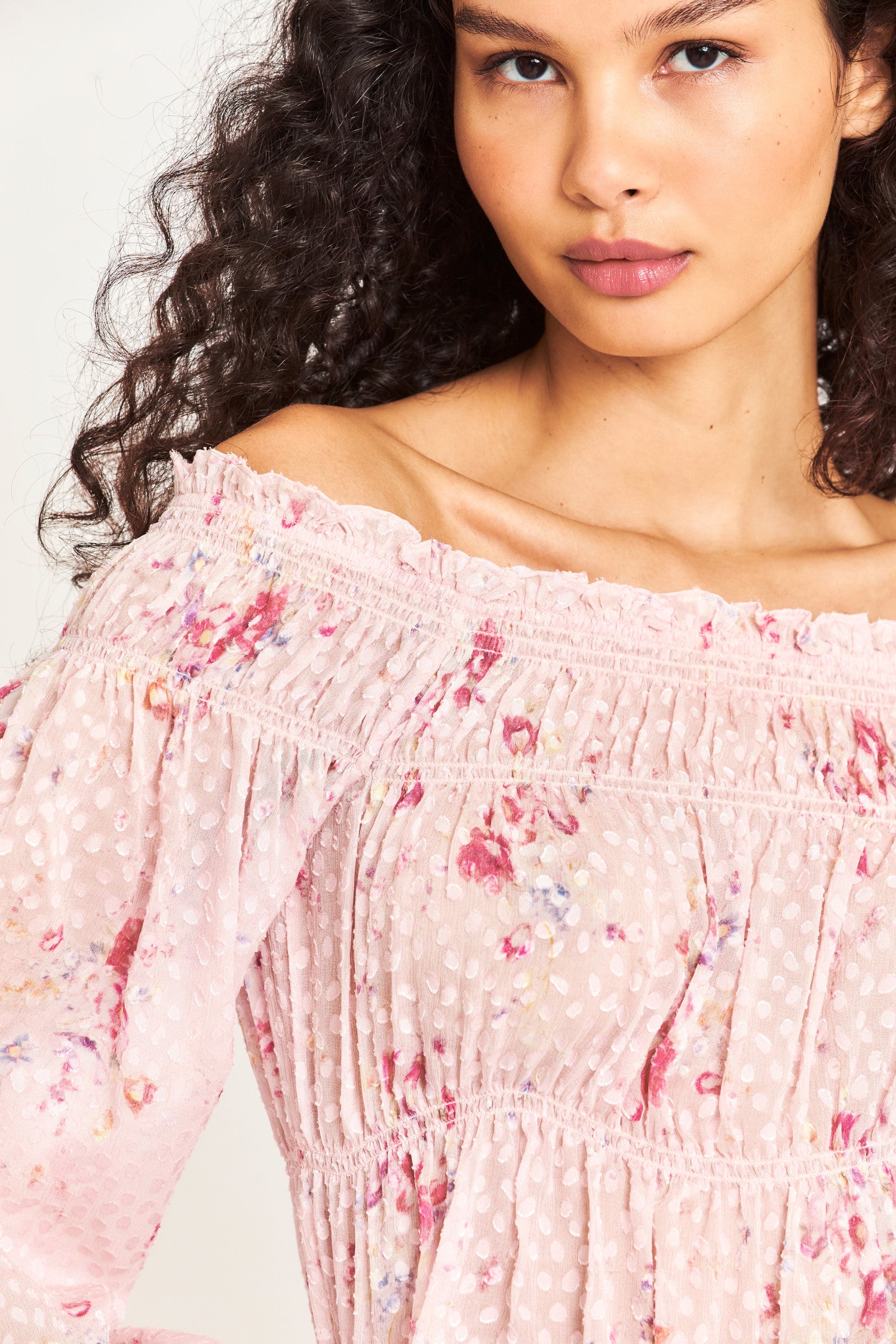 Close up image detailing floral print on pink off the shoulder long sleeve top