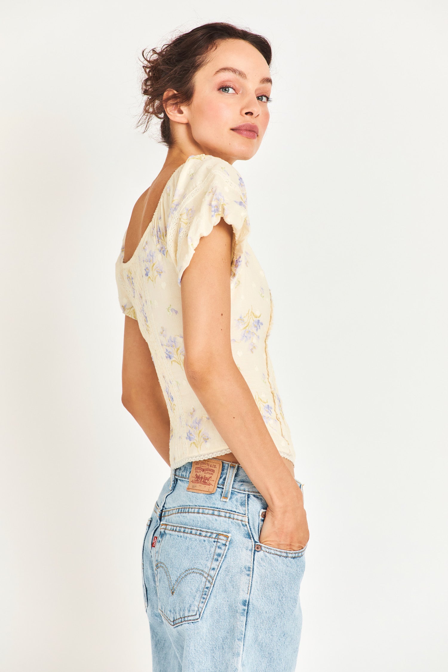 The Zia top is a Victorian-inspired soft yellow fitted corset top that features a stunning textured clip dotted heart shape dobby fabric that gives it an antique feel. It features delicate custom lace detail and an elasticated shoulder to wear off or on the shoulder. It also features a baby blue flower print. 