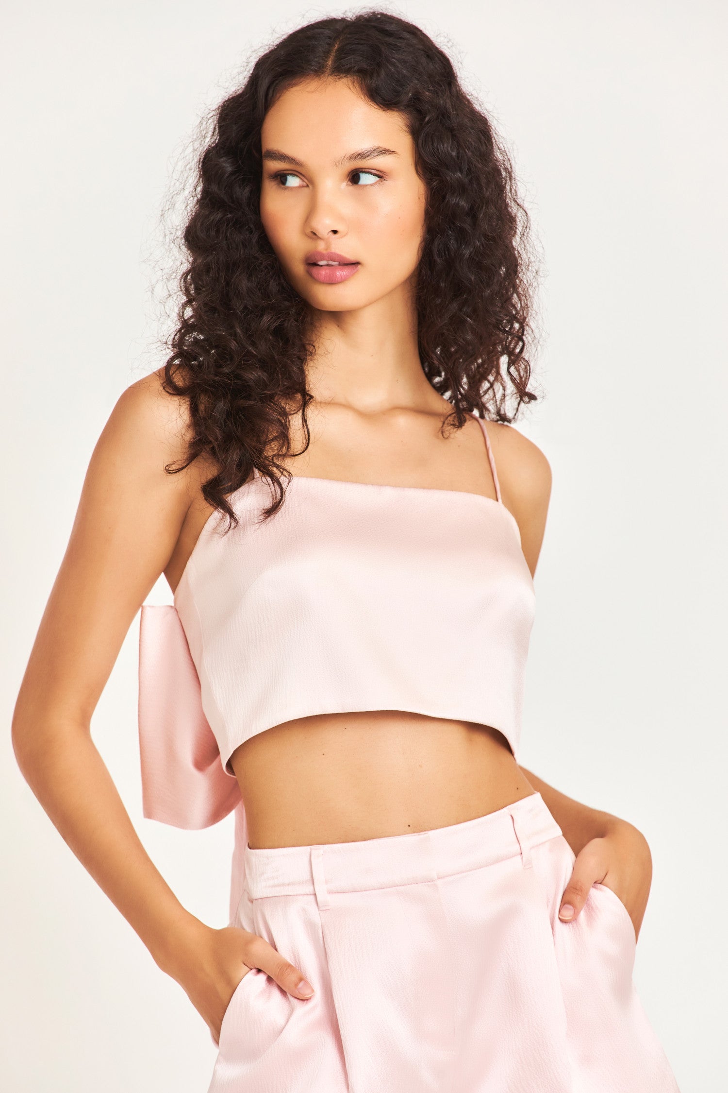 The Roasenna bandeau top is made of 100% silk and is a beautiful soft pink color. It has a side zipper, spaghetti straps, and a dramatic bow in the back. 