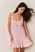 Woman wearing a pink dress against a plain background