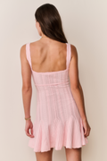 Woman wearing a pink dress against a plain background
