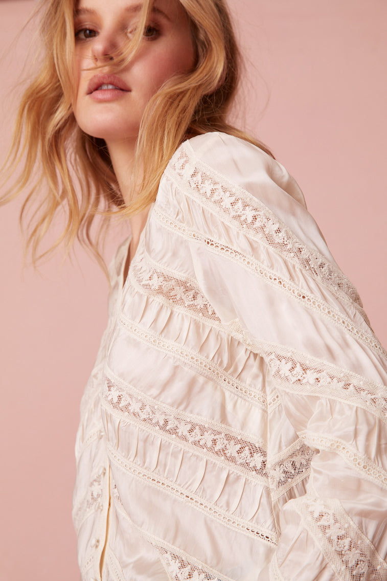 Long sleeve button down top with a v-neckline and diagonal laces for added texture detailing.