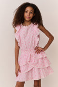 Young girl wearing a pink bow print dress against a plain background