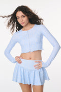 Woman wearing a light blue long-sleeve top and skirt on a white background