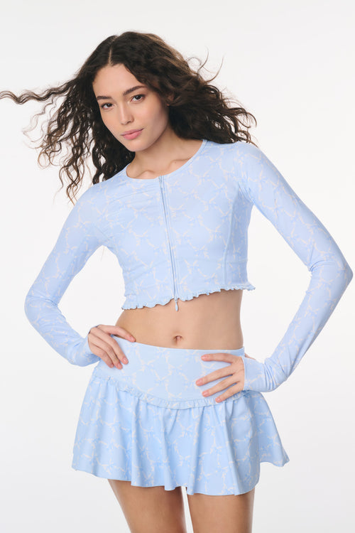 Woman wearing a light blue long-sleeve top and skirt on a white background