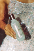 Hand holding a bottle of perfume with a blurred background