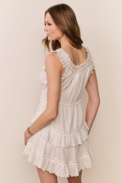 Woman wearing a white lace dress against a plain background