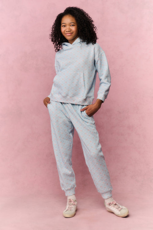 Person wearing a light blue hoodie and pants on a pink background