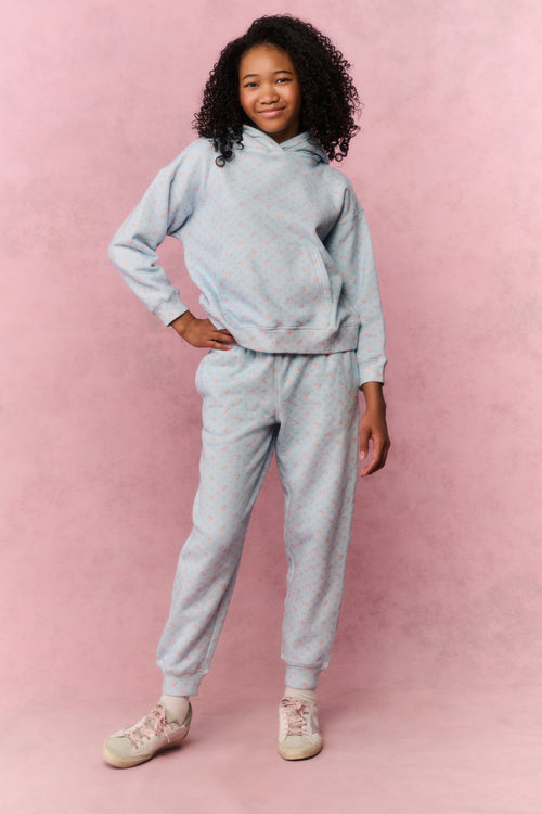 Young girl wearing a blue sweatshirt and pants on a pink background