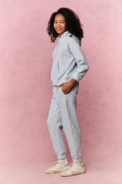 Girl wearing a light blue hoodie and pants set on a pink background