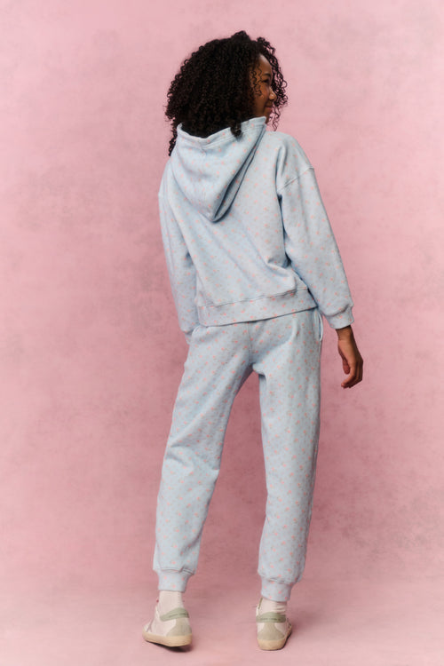 Girl wearing a light blue hoodie and pants set on a pink background