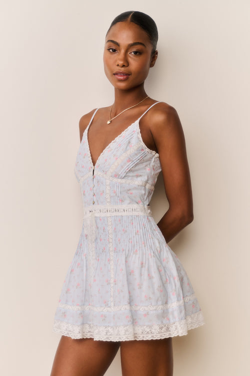 Woman wearing a light blue floral dress against a beige background