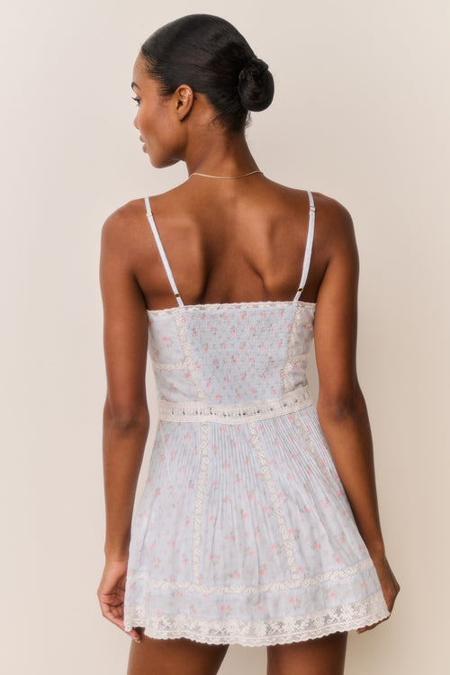 Woman wearing a light blue lace dress with thin straps on a beige background