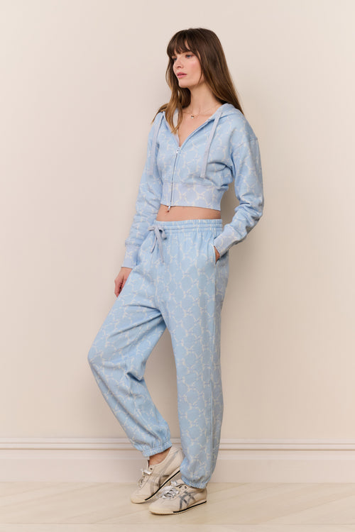 Woman wearing a light blue tracksuit against a beige background