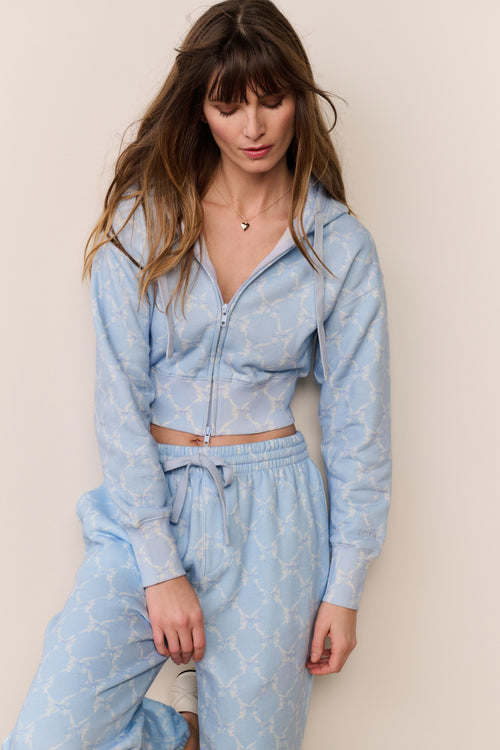 Woman wearing a light blue patterned outfit against a plain background
