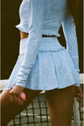 Person wearing a light blue outfit with long sleeves and a skirt.