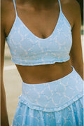 Person wearing a matching blue sports bra and skirt set with a blurred background